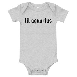 May include: A gray baby onesie with short sleeves and black text that reads "lil aquarius".