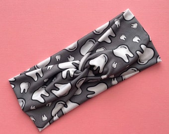 May include: Gray and white knotted headband with a tooth pattern.