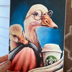 K&ouml;nnte beinhalten: Ein Aquarellbild einer Gans, die eine Brille tr&auml;gt und eine kleinere Gans auf dem R&uuml;cken tr&auml;gt. Die Gans h&auml;lt eine Kaffeetasse mit einem gr&uuml;nen Logo, das eine Gans enth&auml;lt. Der Hintergrund ist ein blauer Aquarell-Wasch.