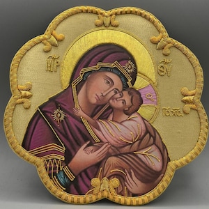 May include: Embroidered icon featuring the Virgin Mary and Child, rendered in soft hues of purple, pink, and gold. The artwork is framed by a gold, flower-shaped border with intricate detailing. The icon's design includes traditional religious symbols.