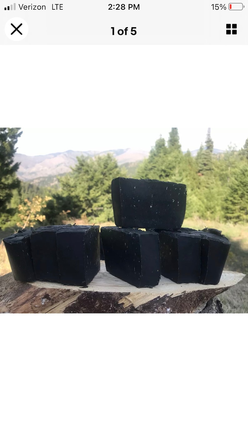 Peut inclure: Cinq savons noirs dispos&eacute;s sur une surface en bois. Le savon est dans un environnement naturel avec des arbres et des montagnes en arri&egrave;re-plan.