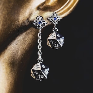 May include: Silver dangle earrings with a blue gemstone and a silver 20-sided die charm.