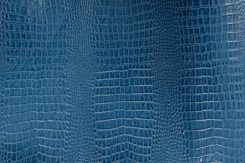 May include: A close-up of a blue textured fabric with a crocodile skin pattern.