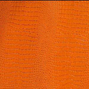 May include: Orange textured fabric with a crocodile skin pattern.