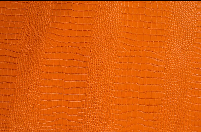 May include: Orange textured fabric with a crocodile skin pattern.