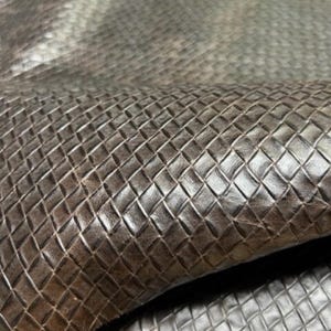 May include: Close-up of a brown leather fabric with a diamond-shaped embossed pattern.
