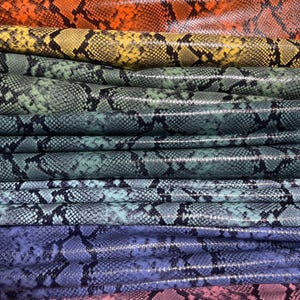 May include: A stack of colorful snakeskin leather in various shades of red, orange, yellow, green, blue, and pink.