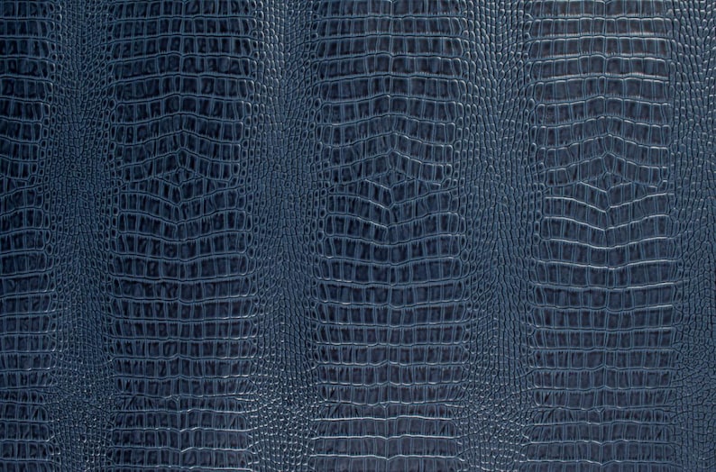 May include: Close-up of a dark blue textured fabric with a crocodile skin pattern.