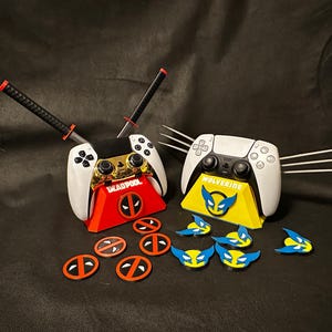 May include: Two white PlayStation 5 controllers are displayed on stands. The stand on the left is red with a Deadpool logo and two katana swords. The stand on the right is yellow with a Wolverine logo and three claws. There are several Deadpool and Wolverine logos scattered around the stands.