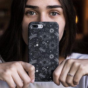 May include: A black phone case with a white celestial design featuring moons, stars, and suns. The design is repeated throughout the case.
