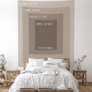 May include: A tapestry with the text "Shores of Moon" in a gold script font. The tapestry is shown in four different sizes: X-Large (88" x 104"), Large (68" x 80"), Medium (51" x 60"), and Small (26" x 36"). The tapestry is displayed on a wall behind a bed with white bedding.