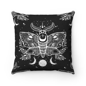 May include: Black and white throw pillow with a moth design. The moth has intricate details and is surrounded by crescent moons and stars. The background is black.