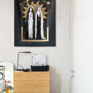 May include: A black tapestry with a gold frame and two figures in white dresses with long hair. The figures are standing in front of a large gold star with a crescent moon above it. The background is a dark blue with gold stars.