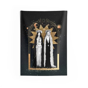 May include: Two figures in white and black gowns stand within a gold starburst frame against a black background with gold stars. The figures wear crowns and have long hair. The frame is surrounded by a gold archway with celestial symbols.