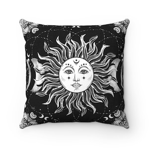 Puede incluir: Almohada de color negro y blanco con un dise&ntilde;o de sol y luna. El sol tiene una cara y la luna est&aacute; en varias fases.