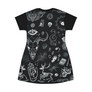 Może przedstawiać: Czarna sukienka z t-shirtu z białym nadrukiem r&oacute;żnych symboli okultystycznych i mistycznych, w tym czaszki, węża, sowy, ćmy, jelenia, dłoni, krzyża, klucza, książki i ważki.