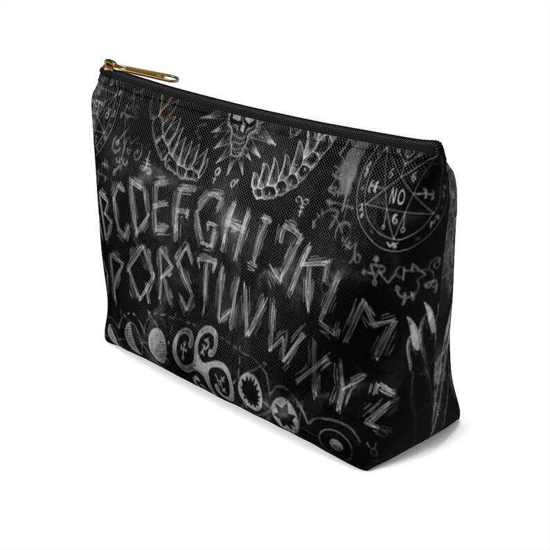May include: Black and white makeup bag with a white ouija board design. The bag features the letters of the alphabet, numbers, and symbols.
