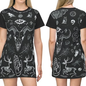 Może przedstawiać: Czarna sukienka z t-shirtu z białym nadrukiem na całej powierzchni r&oacute;żnych symboli okultystycznych i mistycznych, w tym czaszki, oka, węża, ćmy i szkieletu.