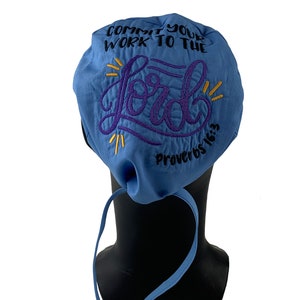 Può includere: Un berretto chirurgico blu con il testo "Commit your work to the Lord" e "Proverbs 16:3" ricamato in viola e nero.