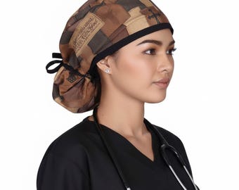 May include: A brown and tan patterned scrub cap with a black trim and tie. The cap features a patchwork design and text that reads "Love Your Gal". The person is wearing a black scrub top and has a stethoscope around their neck.