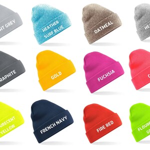 May include: A collection of twelve beanies in various colors, including light grey, heather surf blue, oatmeal, heather grey, graphite, gold, fuchsia, coral, flourescent yellow, french navy, fire red, and flourescent green. Each beanie has the color name printed in white.