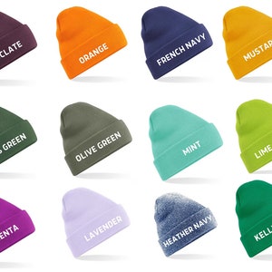 May include: A collection of colorful beanies in various shades, including chocolate, orange, French navy, and mustard. Each beanie displays its color name in white text. Other colors include moss green, olive green, mint, lime green, magenta, lavender, heather navy, and kelly green.