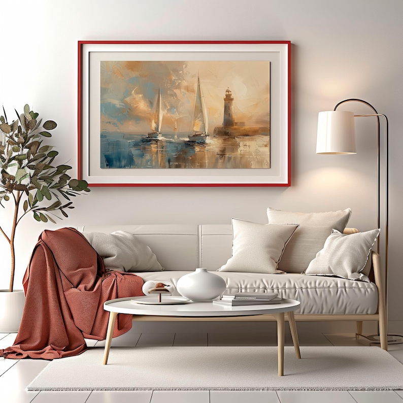 K&ouml;nnte beinhalten: Gerahmtes Gem&auml;lde von Segelbooten und einem Leuchtturm auf dem Wasser. Das Kunstwerk befindet sich in einem roten Rahmen und h&auml;ngt &uuml;ber einem wei&szlig;en Sofa mit Kissen. Eine rostfarbene Decke ist &uuml;ber das Sofa drapiert.