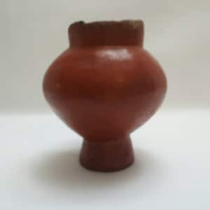 以下が含まれることがあります： 幅広の底と狭い開口部を持つ、小さな丸いテラコッタ製の鉢。鉢は赤褐色です。