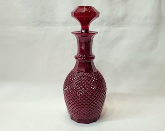 A vintage mid 20th Century ruby red faceted glass decanter with hobnail body and starburst base, probably by Casa Pupo of London, UK.