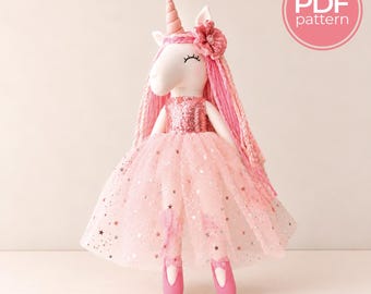 May include: A plush unicorn doll featuring a sequined pink bodice, a layered tulle skirt with star-shaped glitter accents, and long pink yarn hair adorned with a fabric flower. The unicorn wears pink ballet slippers and has a PDF pattern label.