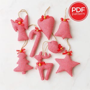 Op de afbeelding: Een verzameling handgemaakte kerstversieringen in diverse vormen, waaronder een engel, hart, bel, zuurstok, vogel, boom, rendier en ster. Elk ornament is gemaakt van rood-wit geruit stof, versierd met rode strikken en gouden accenten. De afbeelding bevat een "PDF pattern" logo.