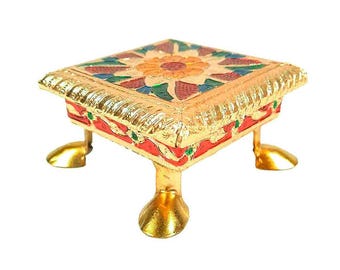 Può includere: Un piccolo supporto quadrato in metallo dorato con quattro gambe curve. La superficie superiore è decorata con un motivo floreale colorato nei toni dell'arancione, del verde e del rosso, mentre i lati sono accentuati da smalto rosso e piccoli dettagli verdi.