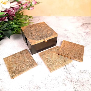 May include: Set of four gold-toned coasters with intricate mandala designs, stored in a black wooden box with a matching mandala design on the lid.