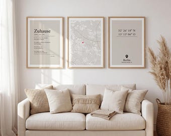 May include: Three framed wall art prints in light wood frames. The left print features the German word Zuhause with text, the center print shows a map with a red heart marker, and the right print displays Berlin coordinates and a location pin icon.