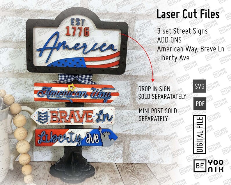 May include: Three wooden signs with red, white, and blue patriotic colors. The top sign says "Est 1776 America". The middle sign says "American Way". The bottom sign says "Brave Ln Liberty Ave".
