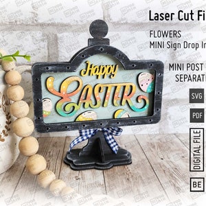 May include: A wooden sign with a black frame and a white background. The sign says "Happy Easter" in colorful letters. The sign is on a black stand with a blue and white checkered ribbon.