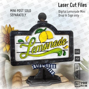 May include: Black and white wooden sign with a lemonade theme. The sign has a distressed look and features a yellow lemon with green leaves, the word "Lemonade" in a stylized font, and a black and white checkered bow. The sign is on a black stand with a round top.