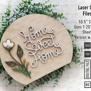 May include: A laser cut wooden sign with the text "Home Sweet Home" in a cursive font. The sign is shaped like a half circle and has a small floral design in the bottom left corner. The sign is 10.5 inches in diameter and uses a 20 inch by 12 inch sheet of wood.