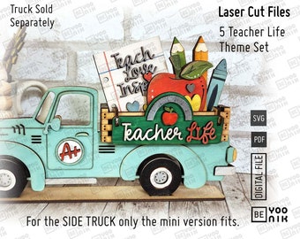 May include: A teal blue toy pickup truck with a wooden bed carrying a variety of school-themed items, including a red apple, pencils, crayons, and a notepad with the words "Teach Love Inspire". The truck has a red "A+" sticker on the side and the words "Teacher Life" on the back.