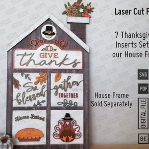 Puede incluir: Un marco de madera con forma de casa con temática de Acción de Gracias. El marco tiene siete insertos intercambiables con diseños como "Give Thanks", "So Blessed", "Gather Together", "Home Baked" y un pavo. Los insertos se venden por separado.