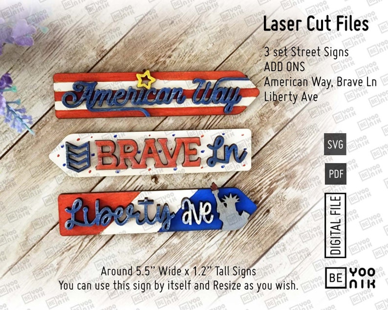 May include: Three laser cut wooden signs with red, white, and blue patriotic colors. The signs read "American Way", "Brave Ln", and "Liberty Ave". The signs are approximately 5.5 inches wide and 1.2 inches tall.