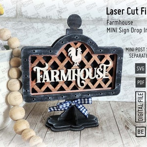 May include: Laser cut farmhouse sign with a rooster and the word "Farmhouse" in a black and brown wood frame. The sign is on a black stand with a blue and white checkered ribbon. The sign is a digital file for download.