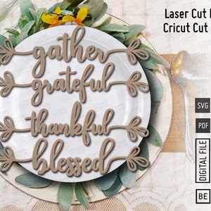 May include: Wooden laser cut files with the words "gather, grateful, thankful, blessed" in a cursive font. The words are arranged on a white plate with greenery. The image also includes the text "Laser Cut Files" and "Cricut Cut Files".