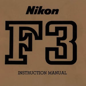 May include: A brown instruction manual for the Nikon F3 camera. The cover features the Nikon logo in black above the large black text "F3". Below the "F3" is the text "INSTRUCTION MANUAL".