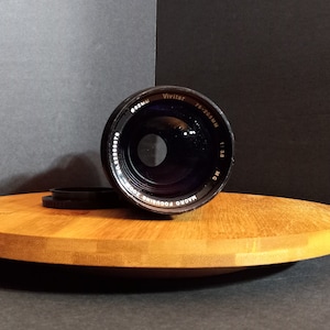 May include: A black Vivitar Series 1 135mm f/2.8 MC Macro Focusing lens with a black lens cap.