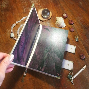 May include: A purple and black leather-bound journal with a decorative clasp and key. The journal is open to reveal blank pages.