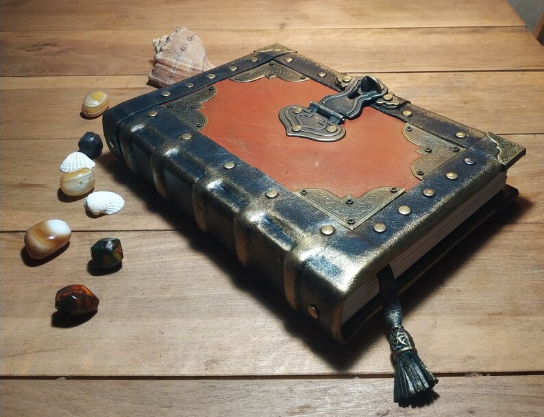 May include: A brown leather-bound journal with a metal clasp and decorative accents. The journal has a distressed look and a tassel.