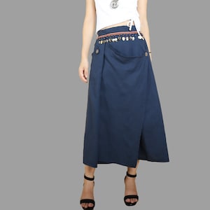 May include: A long, dark blue skirt with a wrap-around design and a decorative belt with silver accents. The skirt has a single button closure on the front.