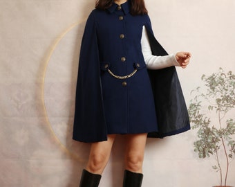 May include: A navy blue cape with a gold chain and buttons. The cape has a collar and a long, flowing design.