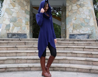 May include: A long-sleeved, hooded tunic in a deep blue color. The tunic has a cowl neck and a high-low hemline. The model is wearing brown knee-high boots.